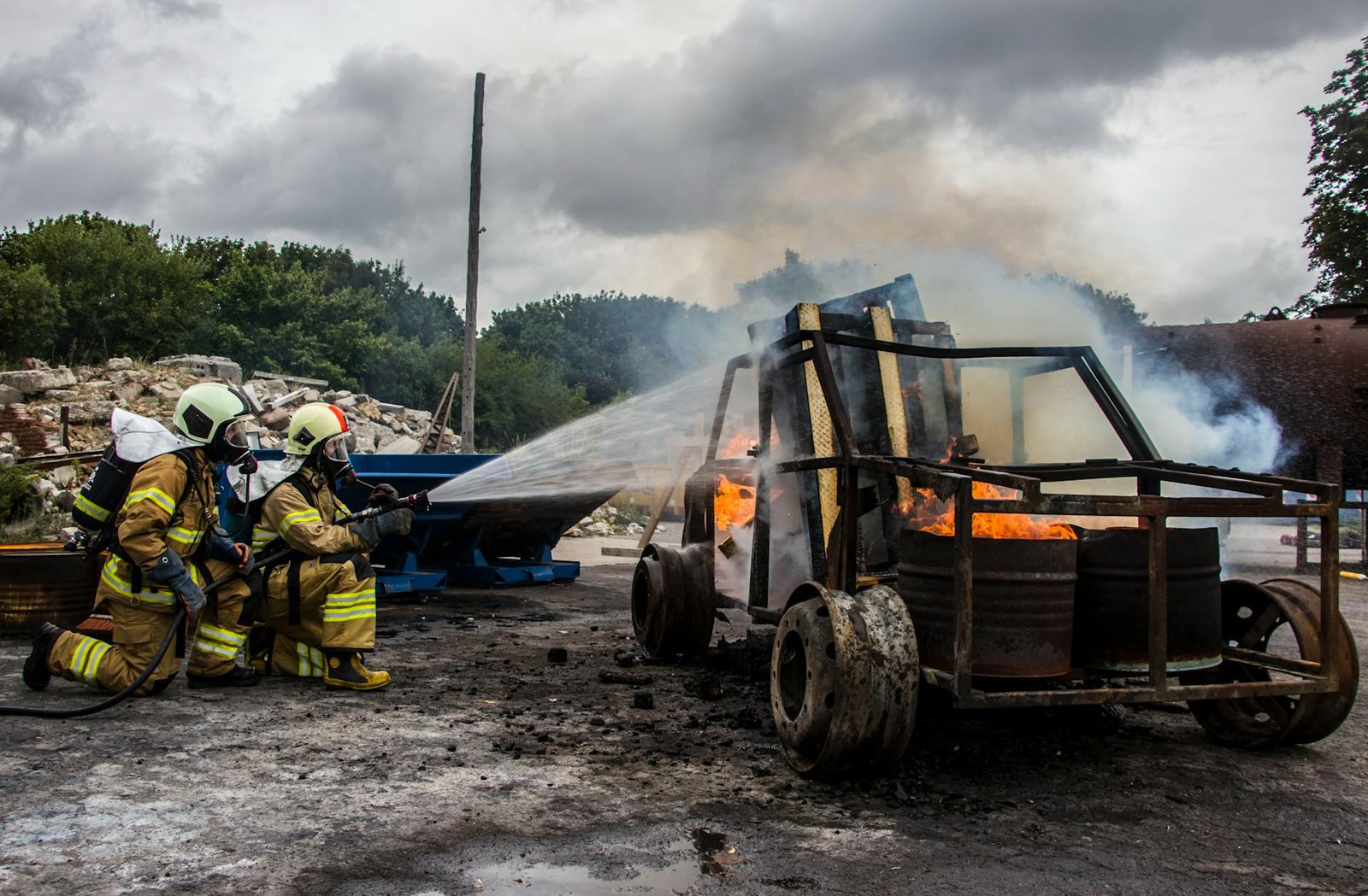 Firefighters in action extinguishing a burning vehicle outdoors, demonstrating skill and teamwork.